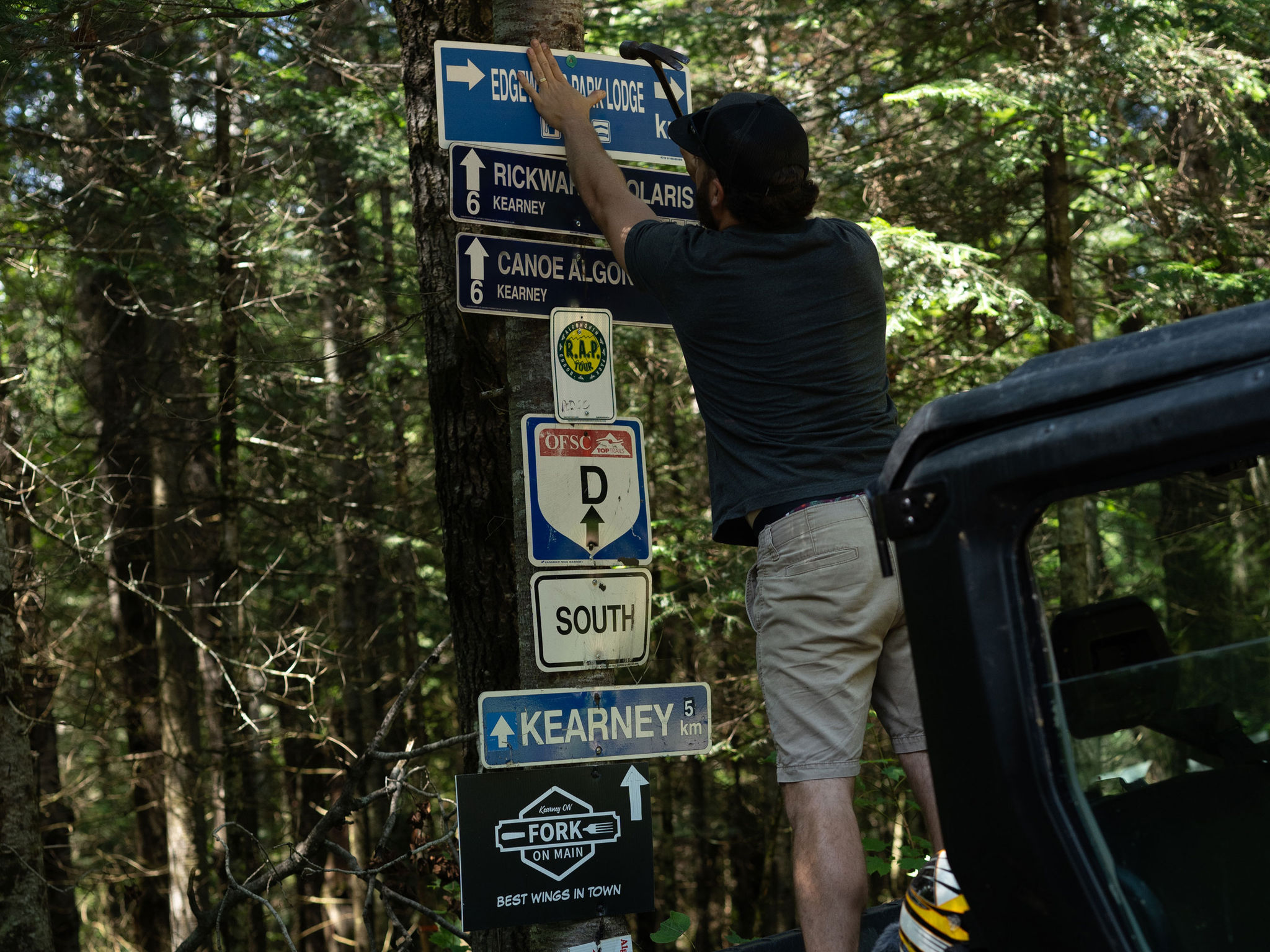 Man hangs signs at a snowmobile trail