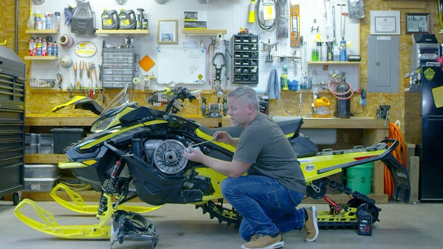 Ski-Doo ambassador Troy Olson doing maintenance on his snowmobile