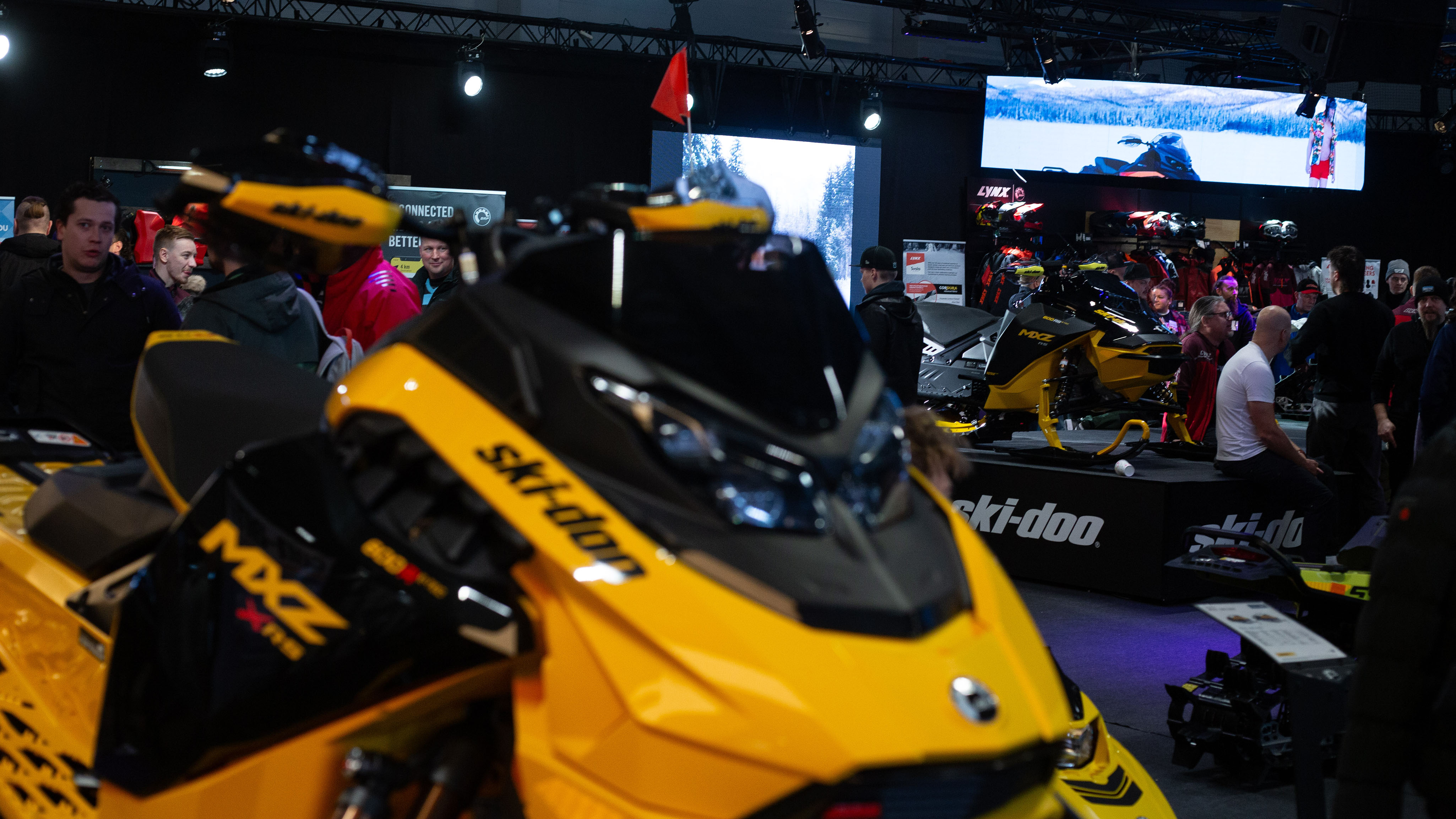 Människor samlade runt Ski-Doo-snöskotrar i en mässhall
