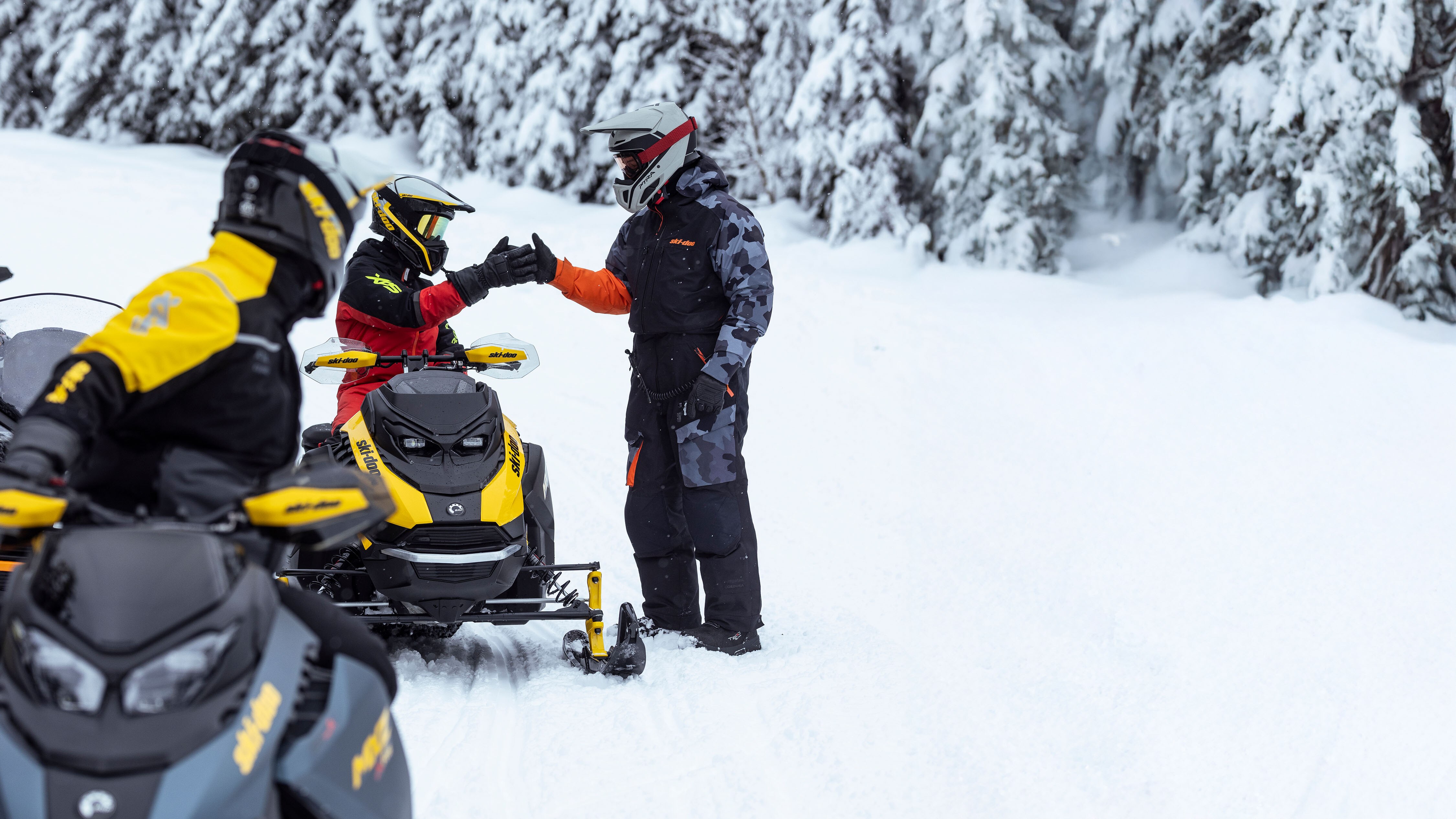 En grupp Ski-Doo-förare som tar en paus och pratar längs leden.