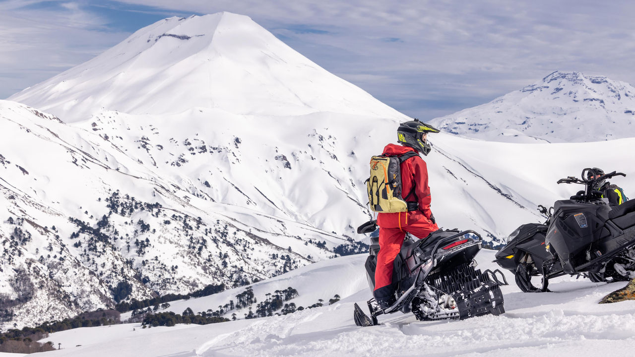 Homme debout sur sa motoneige Ski-Doo au sommet d'une montagne au Chili