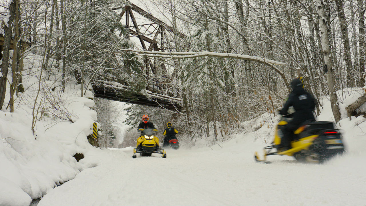 Three riders passing next to each other on a snowmobile trail