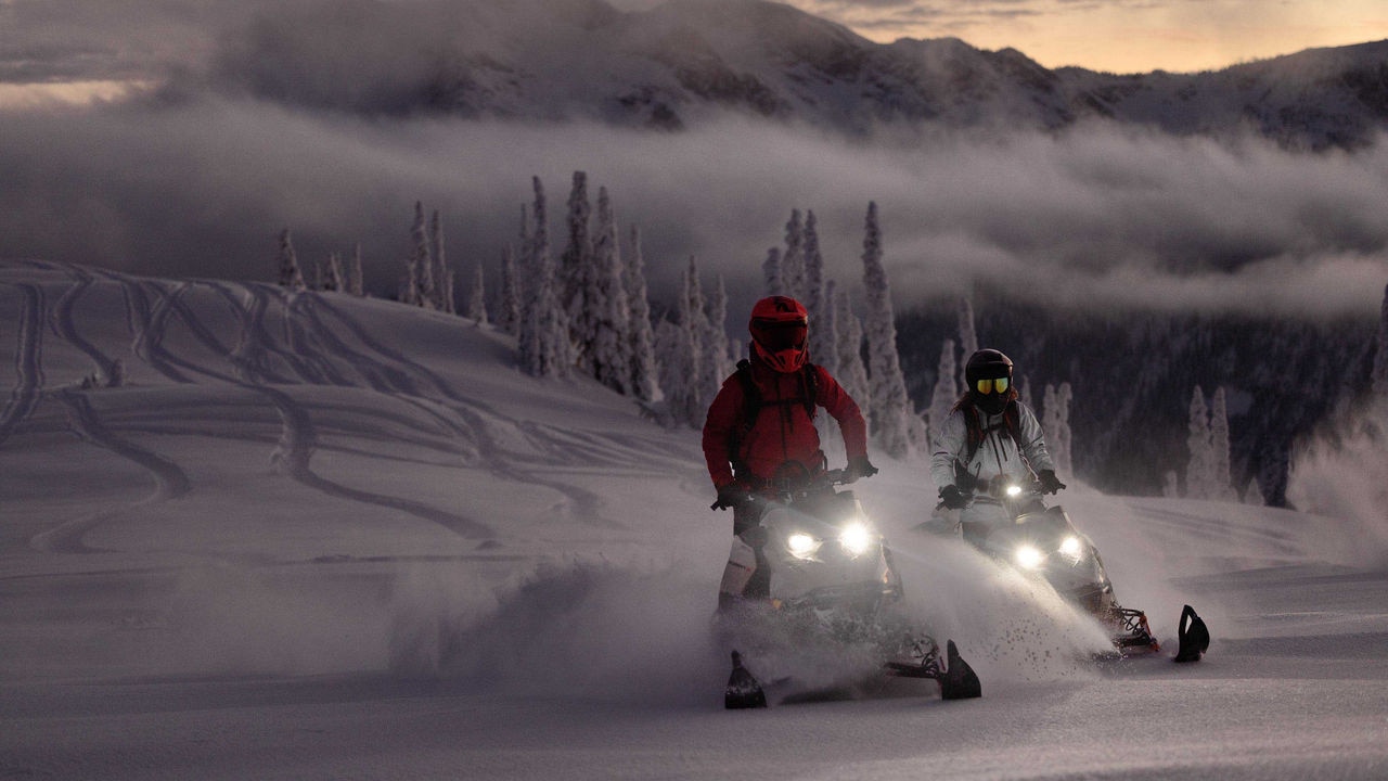 雪上、Ski-Doo Summitに乗っている2人の女性