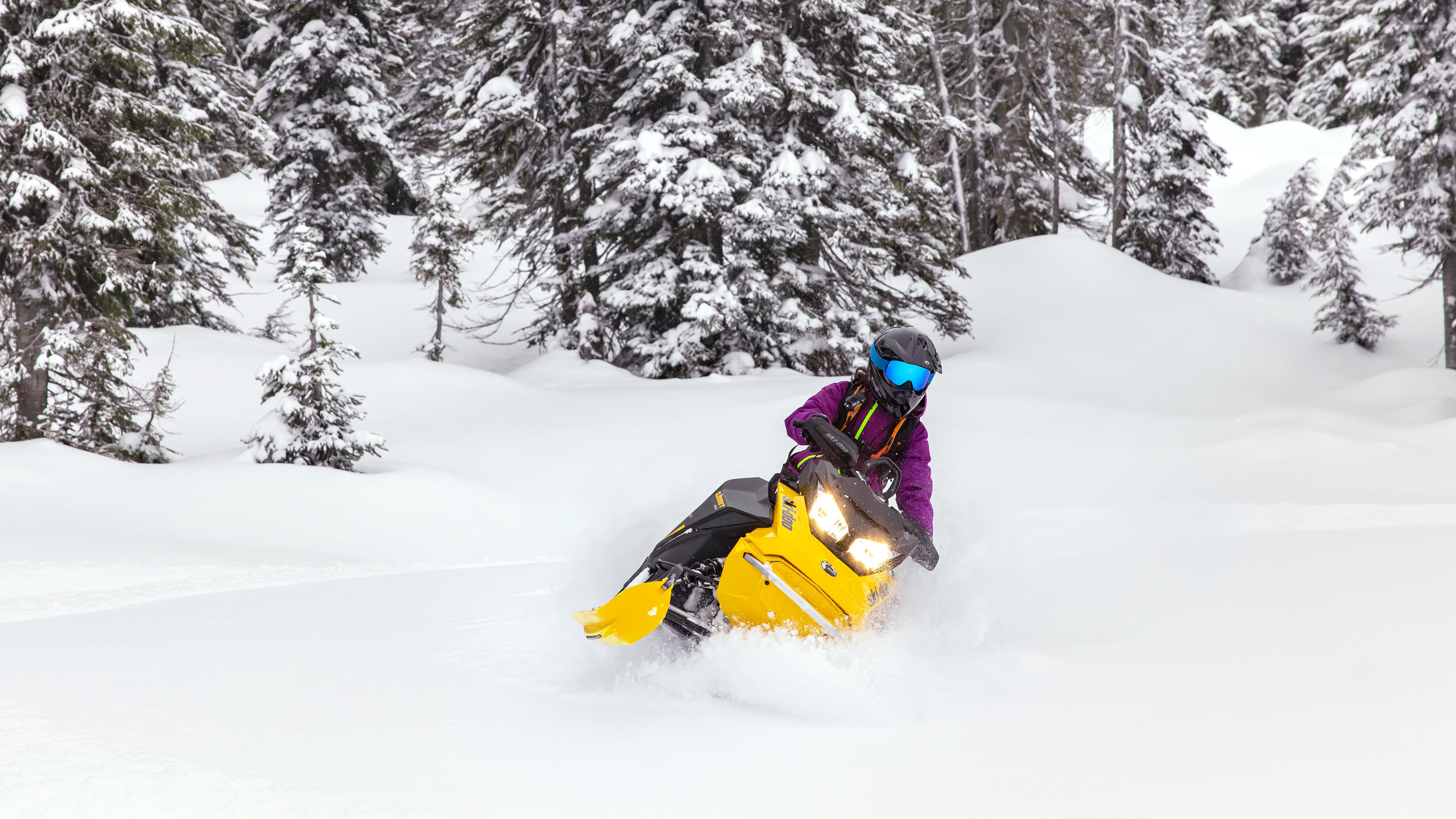 Woman riding a Summit Neo+ snowmobile in deep snow