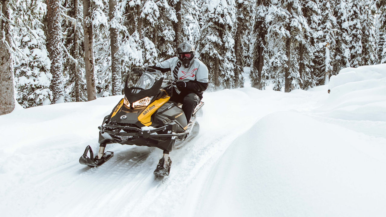 Homme prenant un virage sur un sentier de motoneige au guidon d'un Ski-Doo Tundra