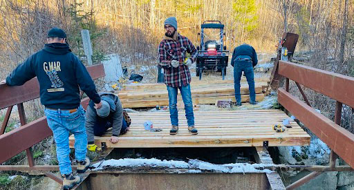 Group working on a bridge for a snowmobile trail