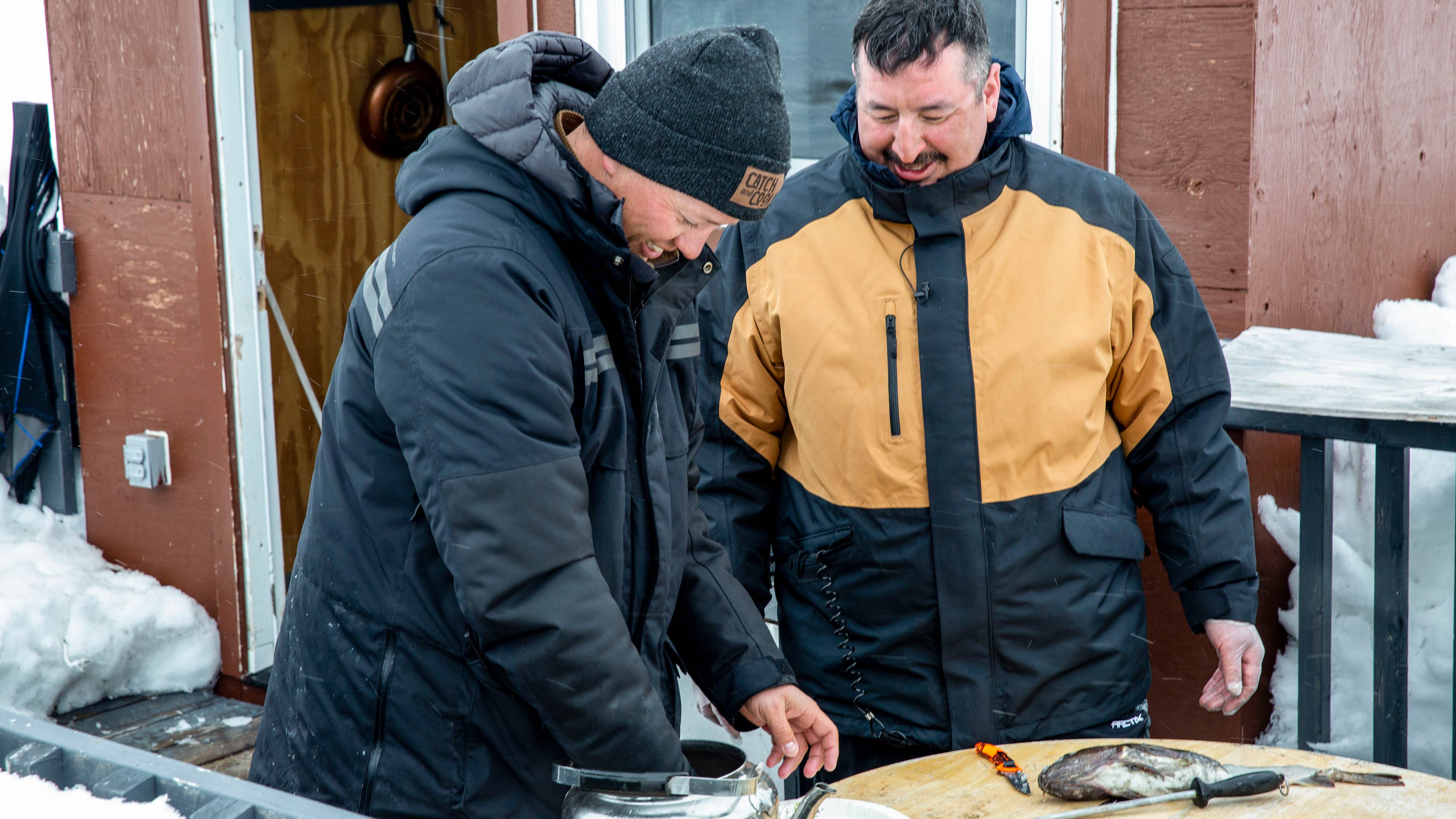 Two men cooking fish