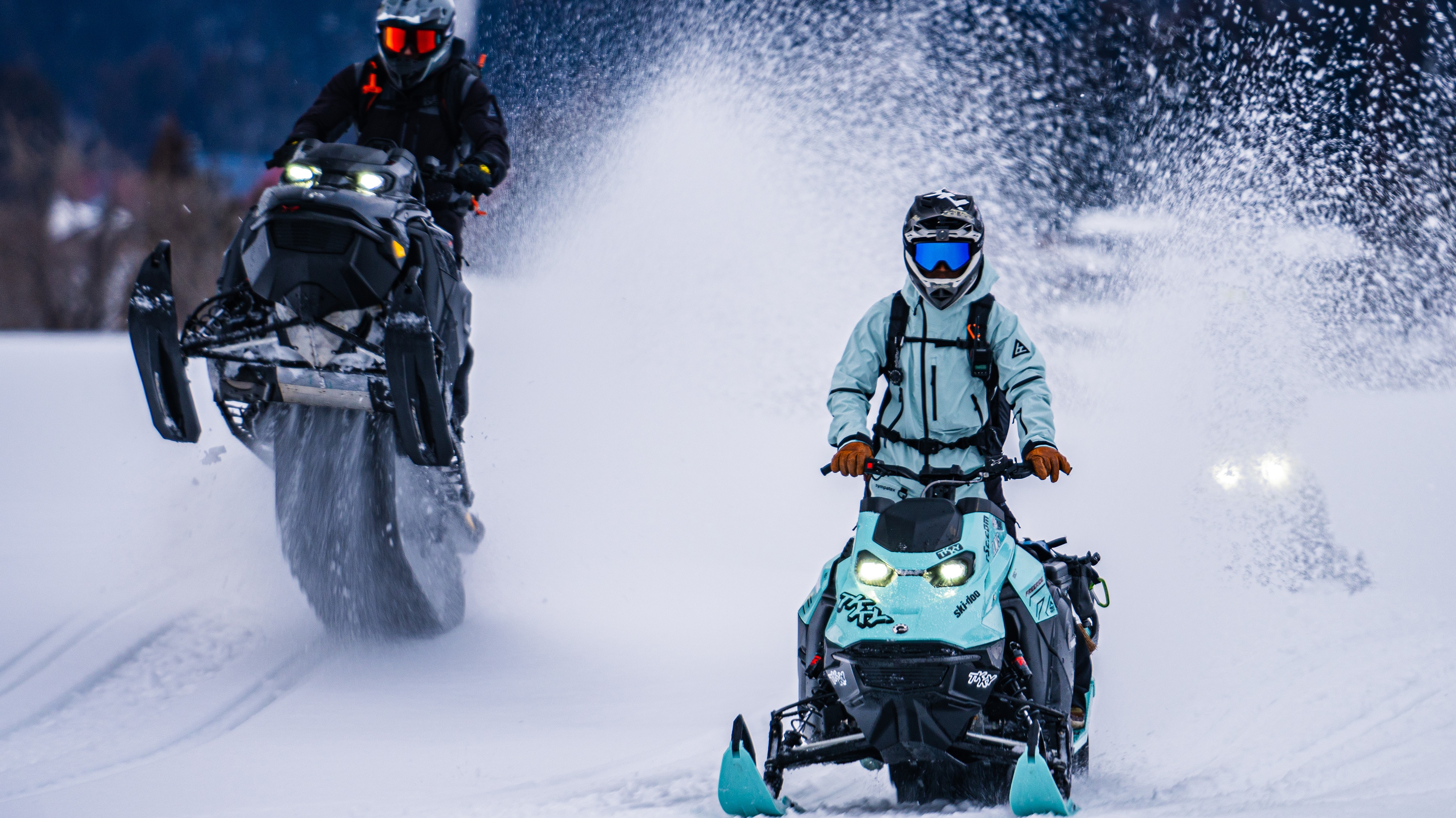 Three people riding their Ski-Doo snowmobiles in the worst weather conditions.