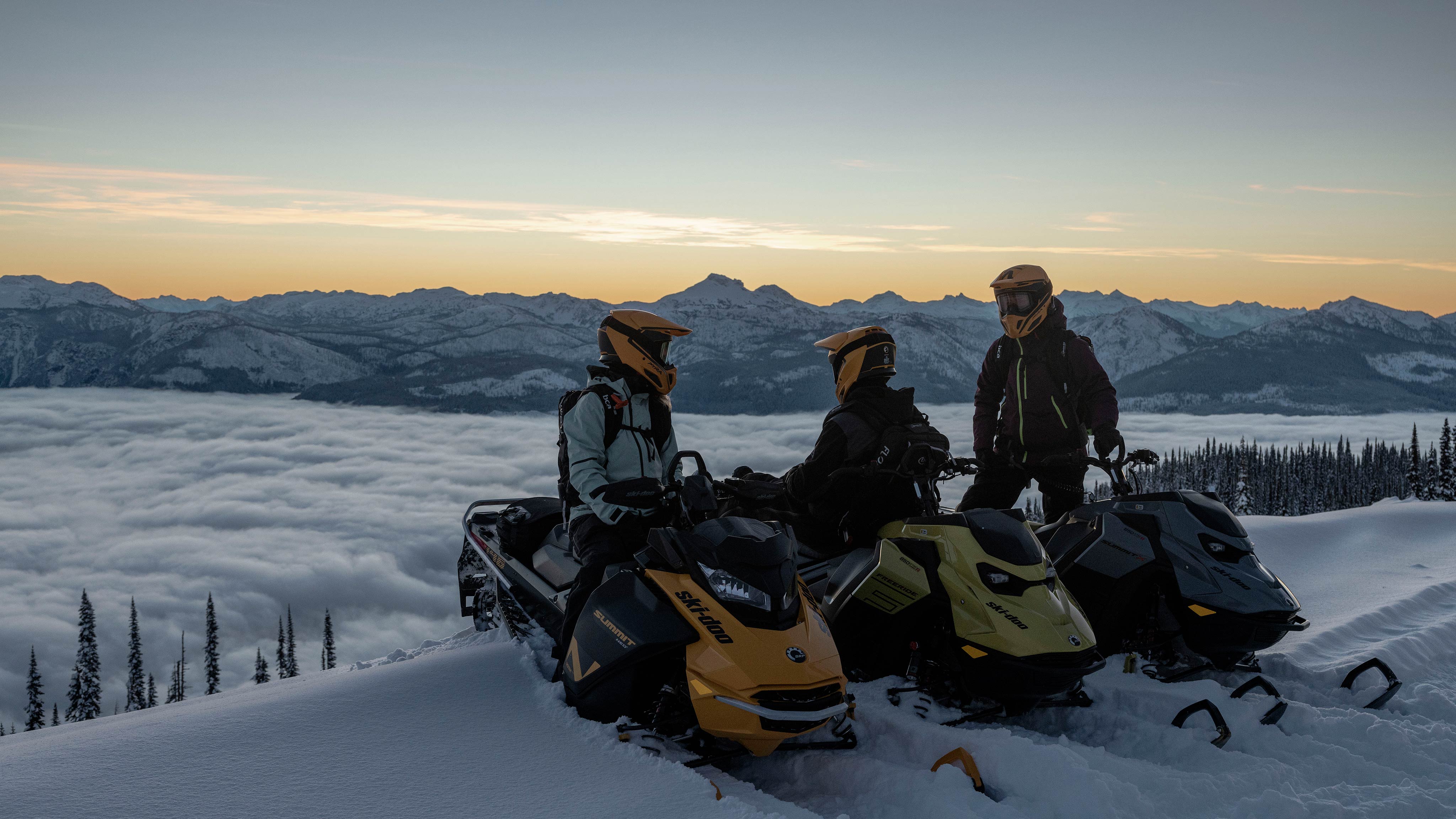 Trois motoneigistes sur leur Ski-Doo au sommet d'une montagne