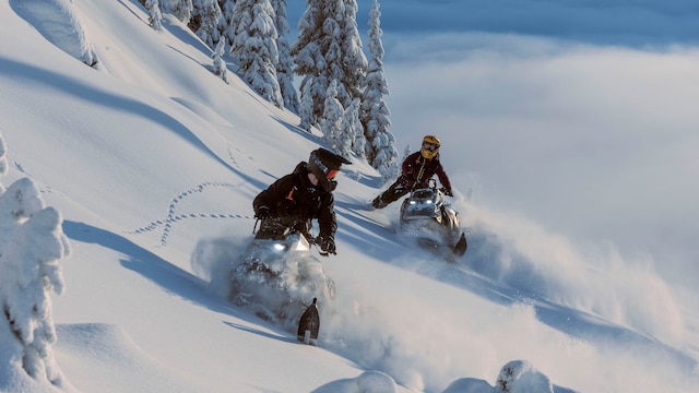 Two Ski-Doo Deep snow snowmobiles riding down a snowy mountain