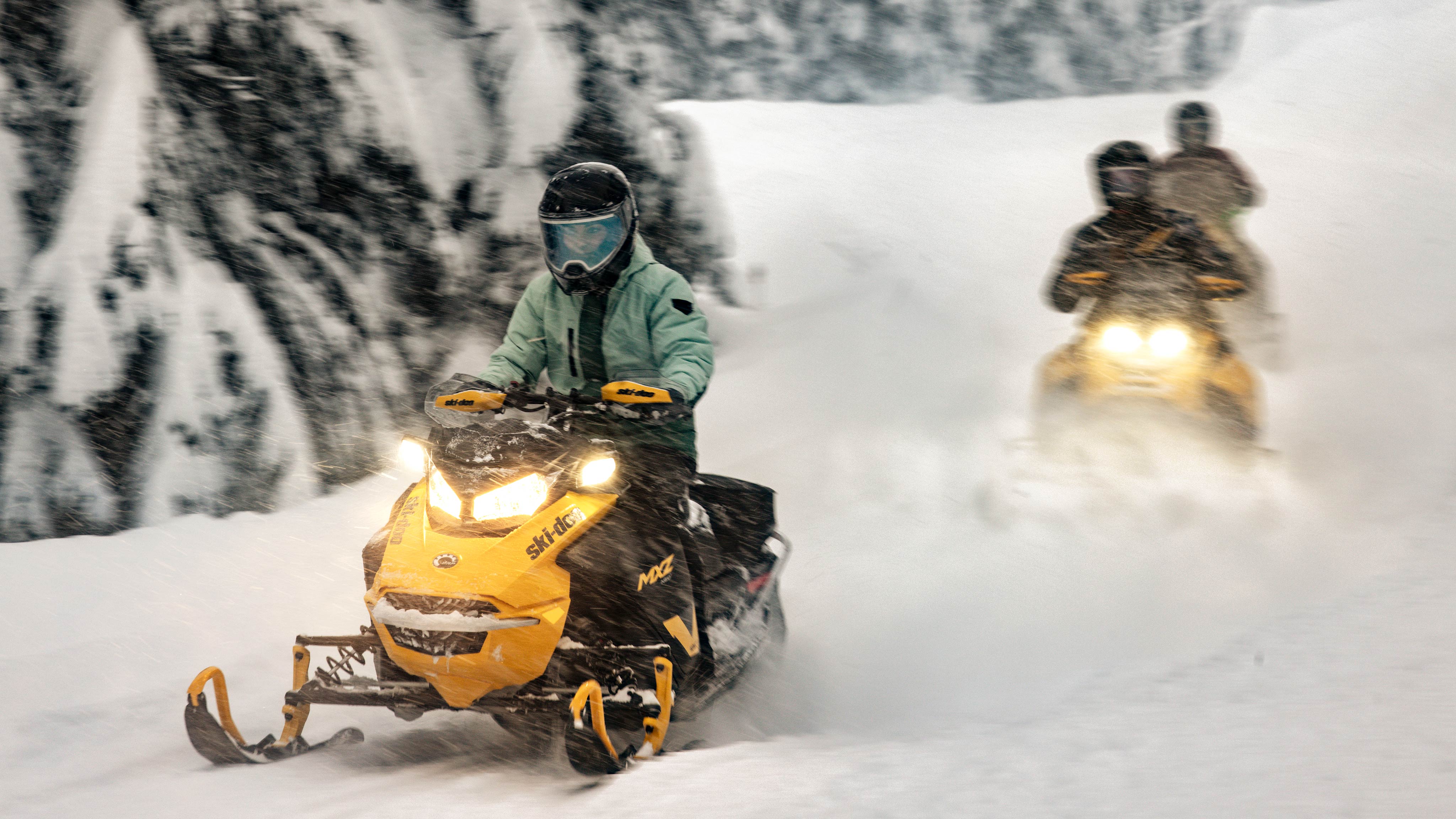 Two 2025 Ski-Doo MXZ NEO trail snowmobile riding in a forest