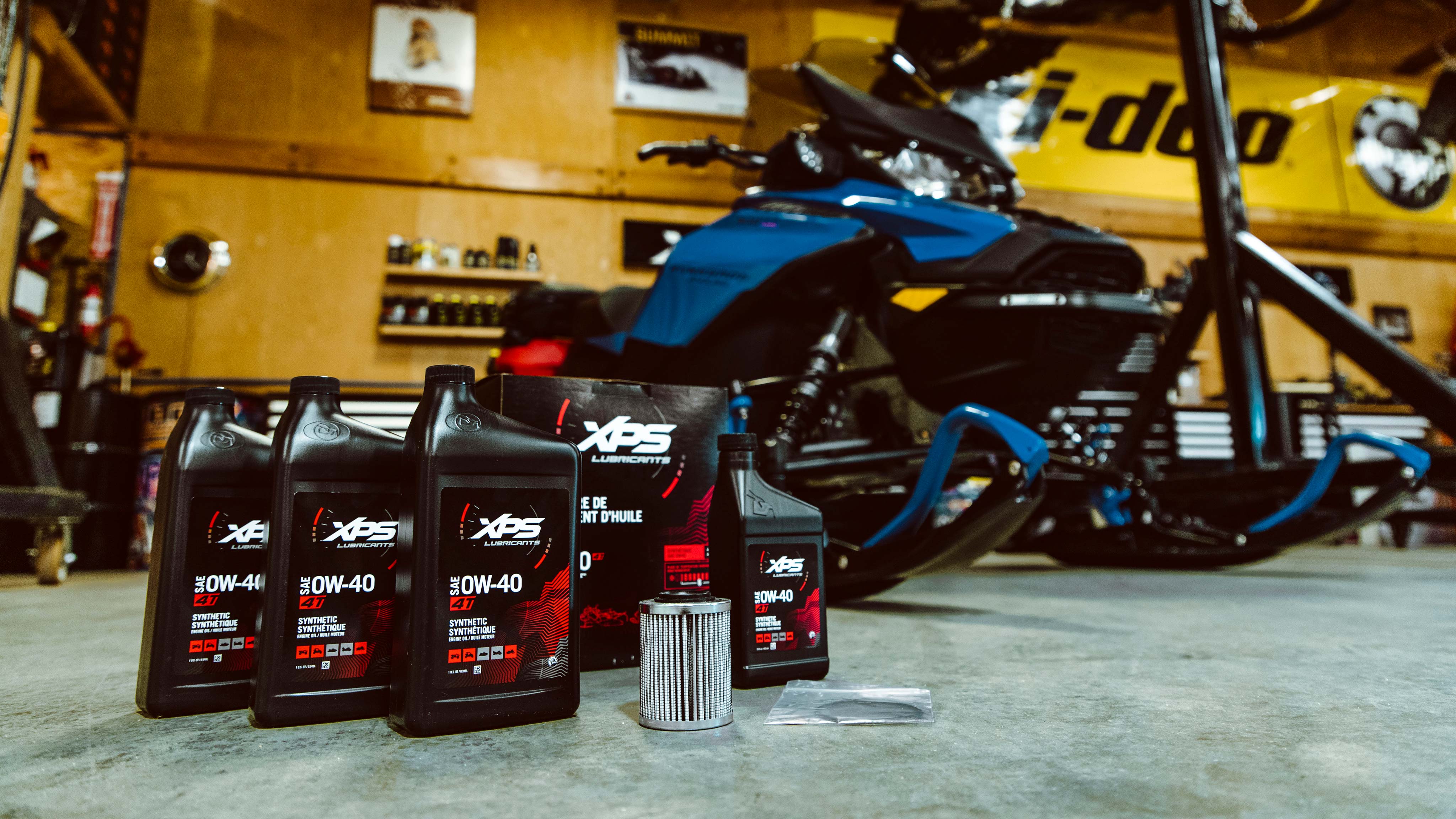 XPS Oil change kit on the floor of a garage and a snowmobile in the background