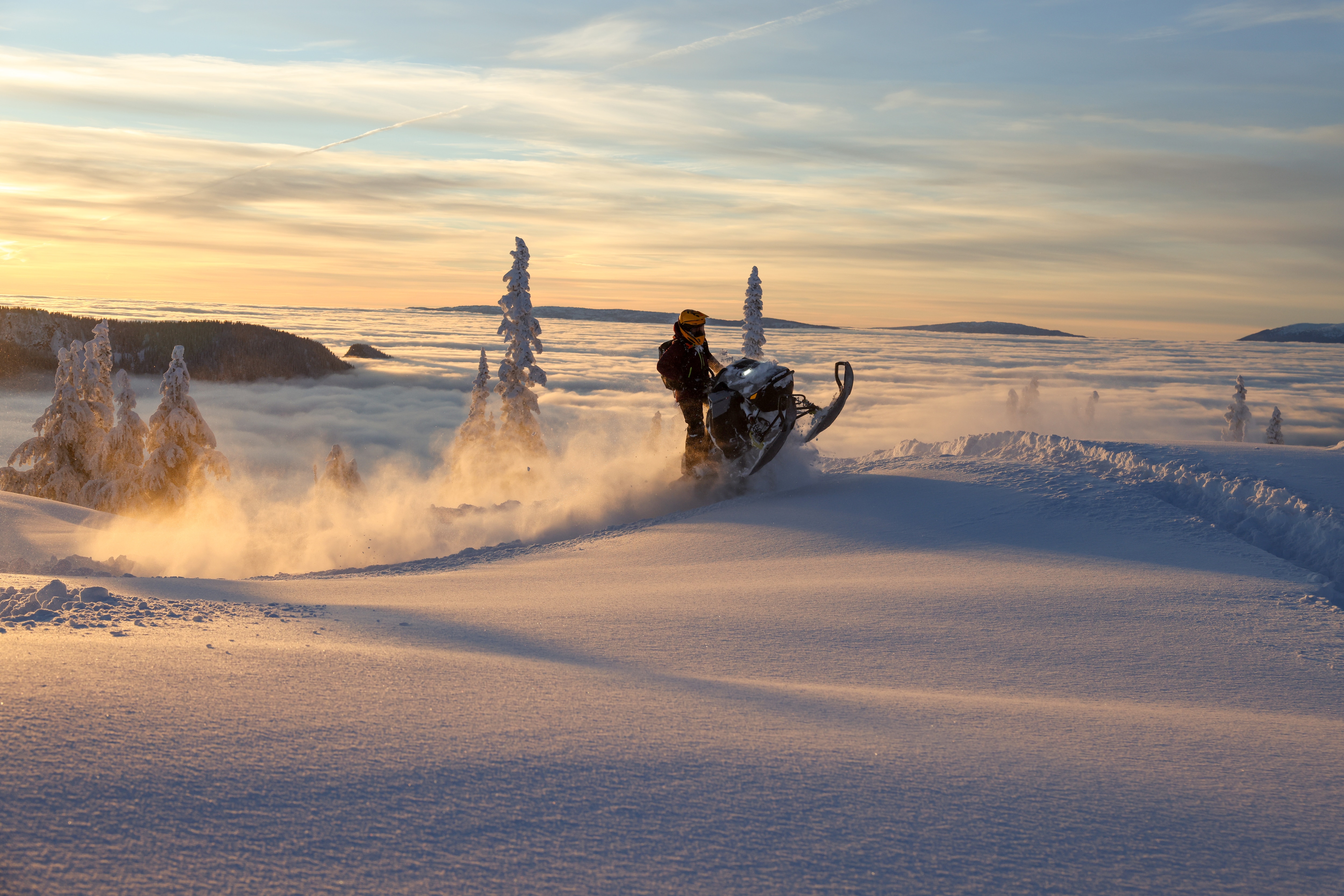 A snowmobiler experiencing the thrill of a Ski-Doo snowmobile riding on a snowy mountain.