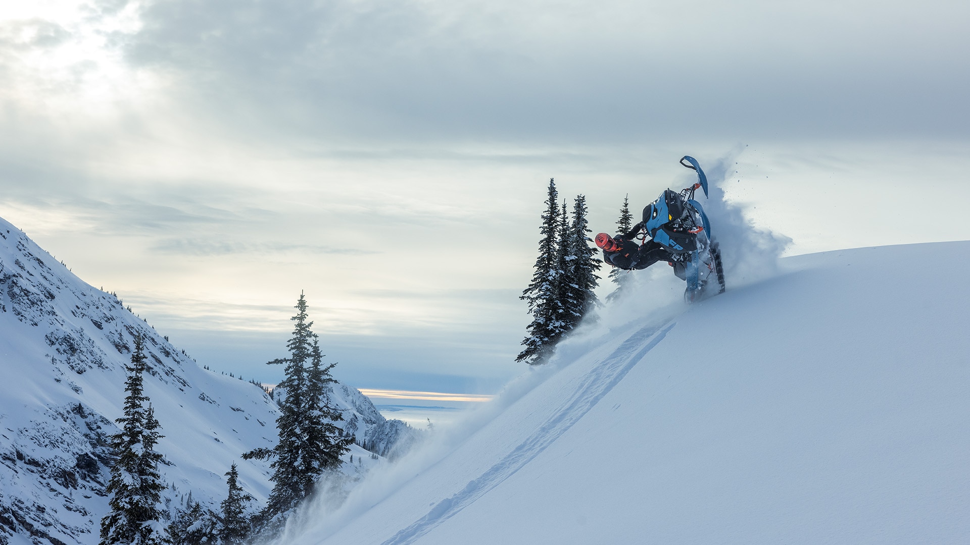 Snowmobiler performing a stunt with a 2026 Ski-Doo Freeride snowmobile on a snow-covered mountain.