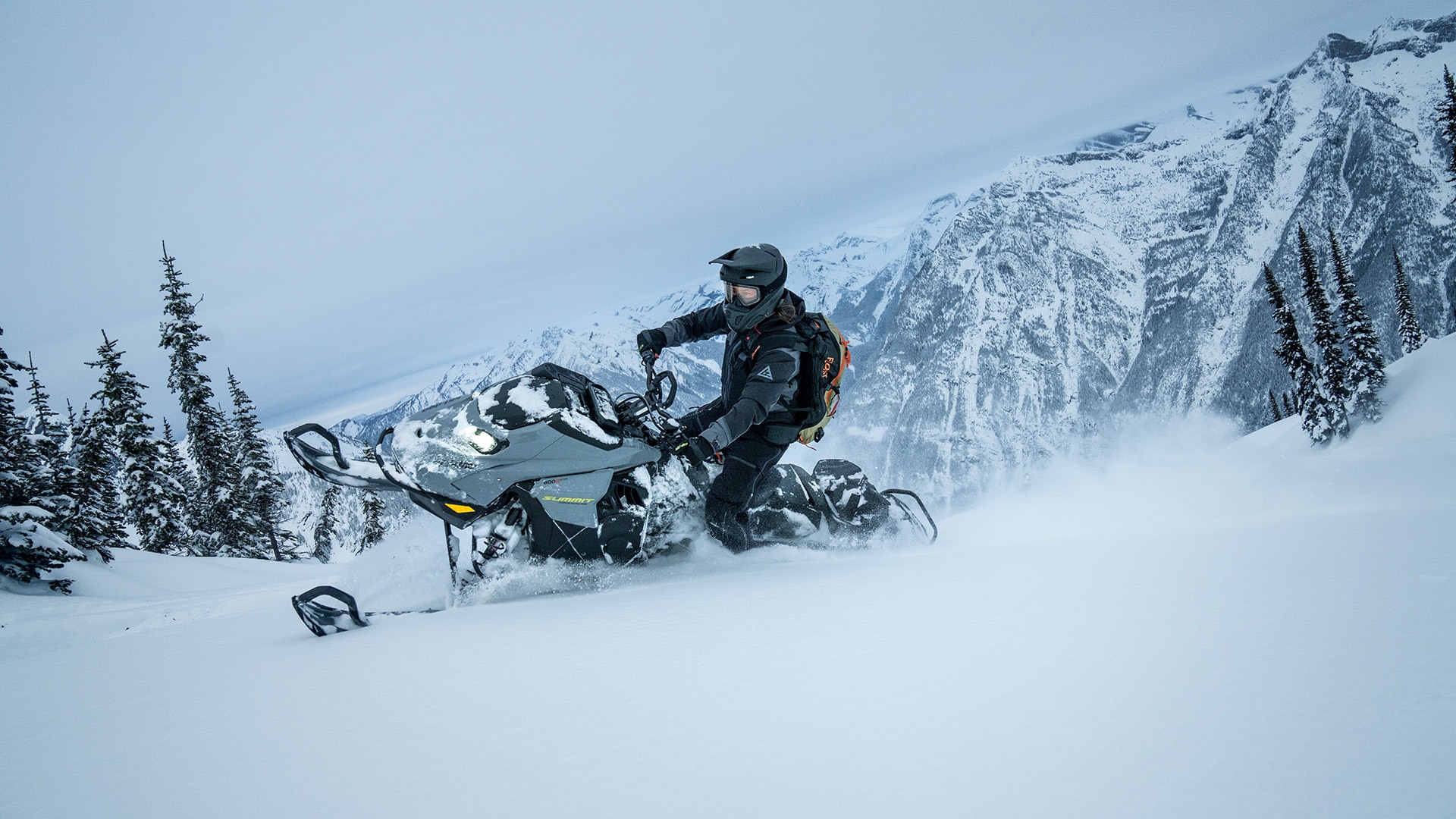 Snowmobiler riding a 2026 Ski-Doo Adrenaline with Edge package through the deep snow of a mountain.