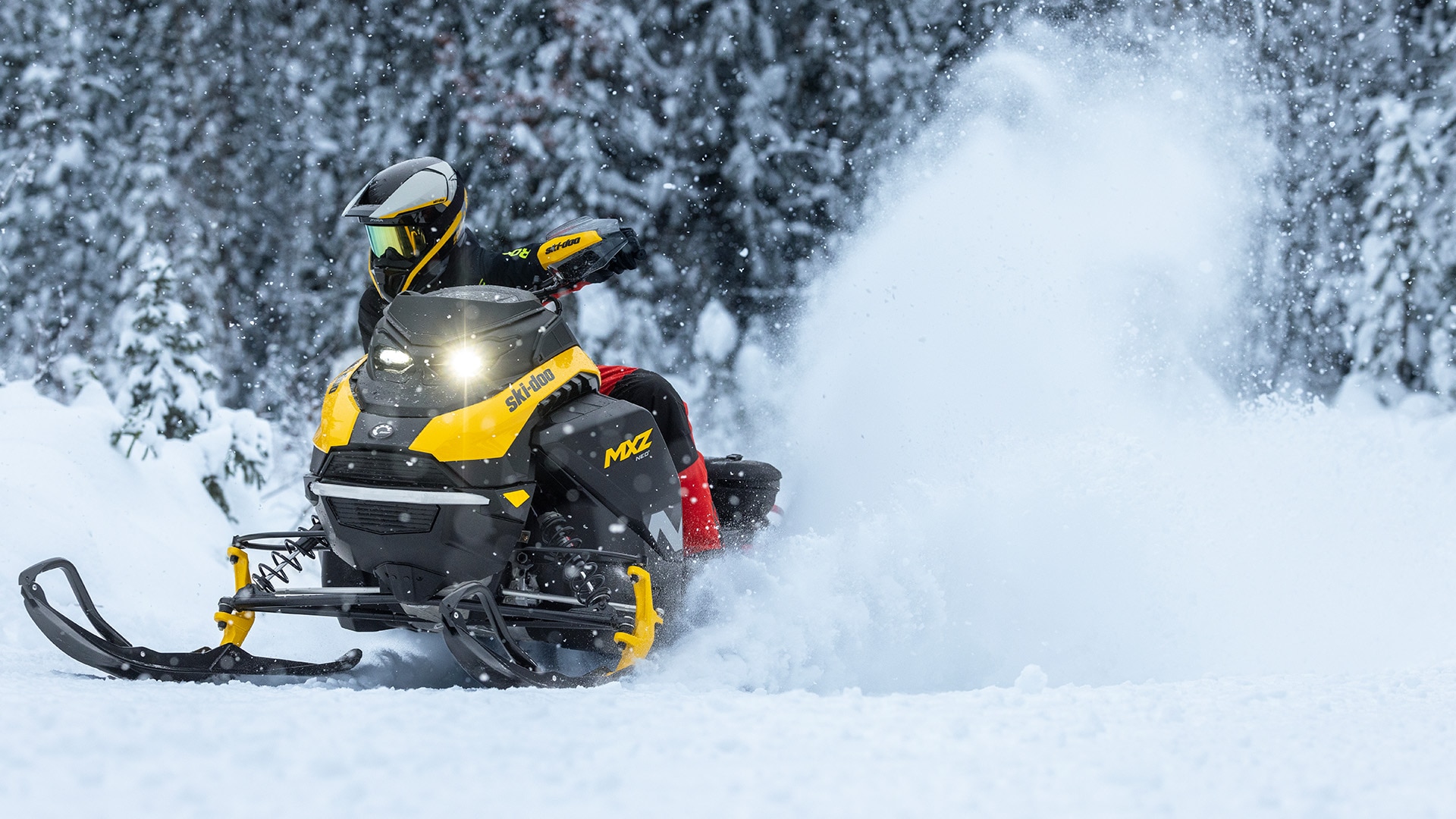 Snowmobiler riding his 2026 Ski-Doo MXZ NEO snowmobile in a snowy forest,