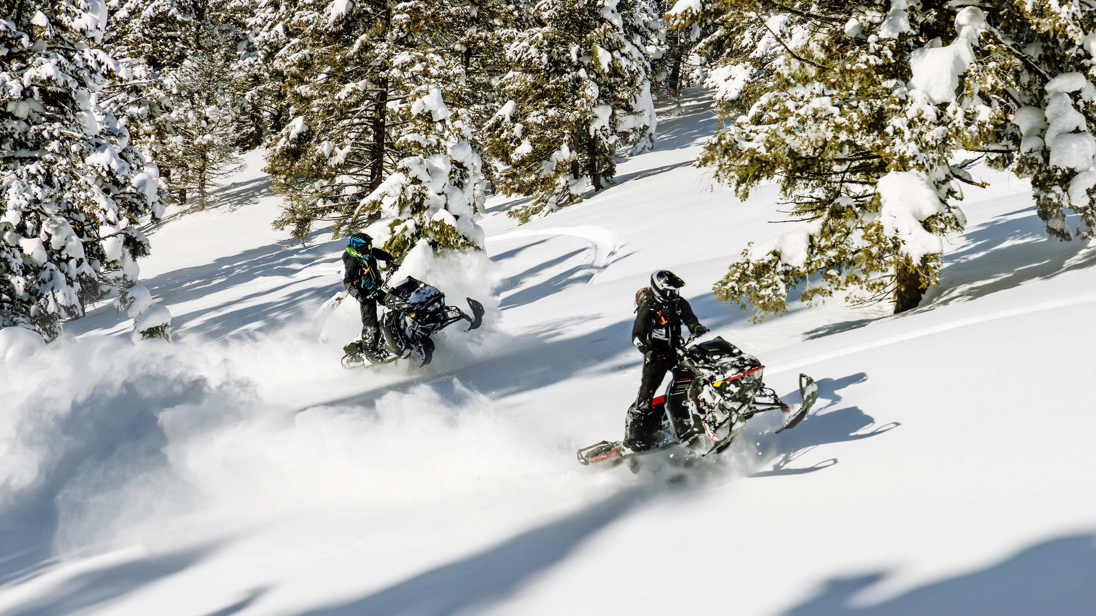 Two riders in deep snow with Ski-Doo snowmobiles