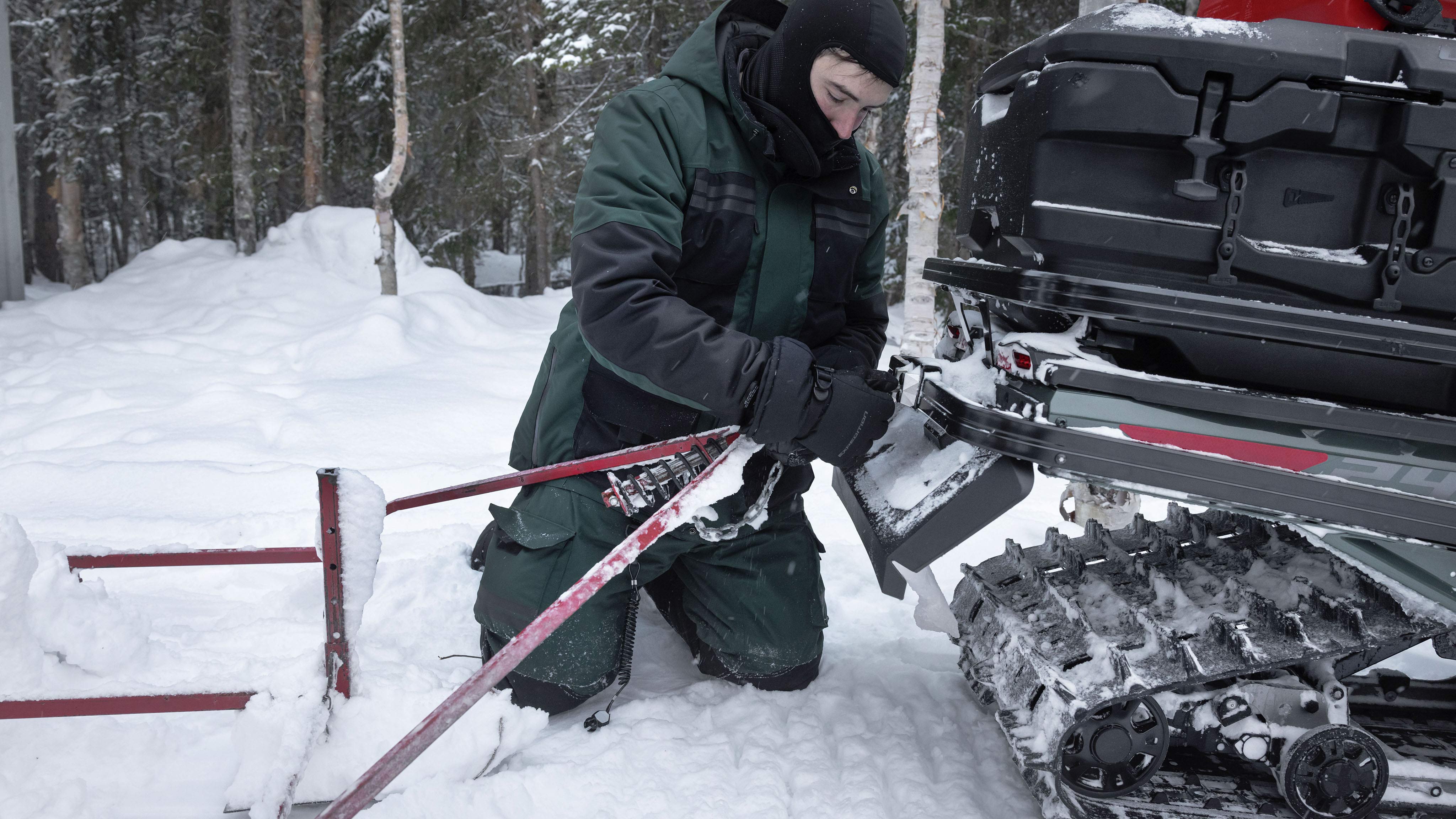 A man attaching a trailer to his Ski-Doo Tundra snowmobile.