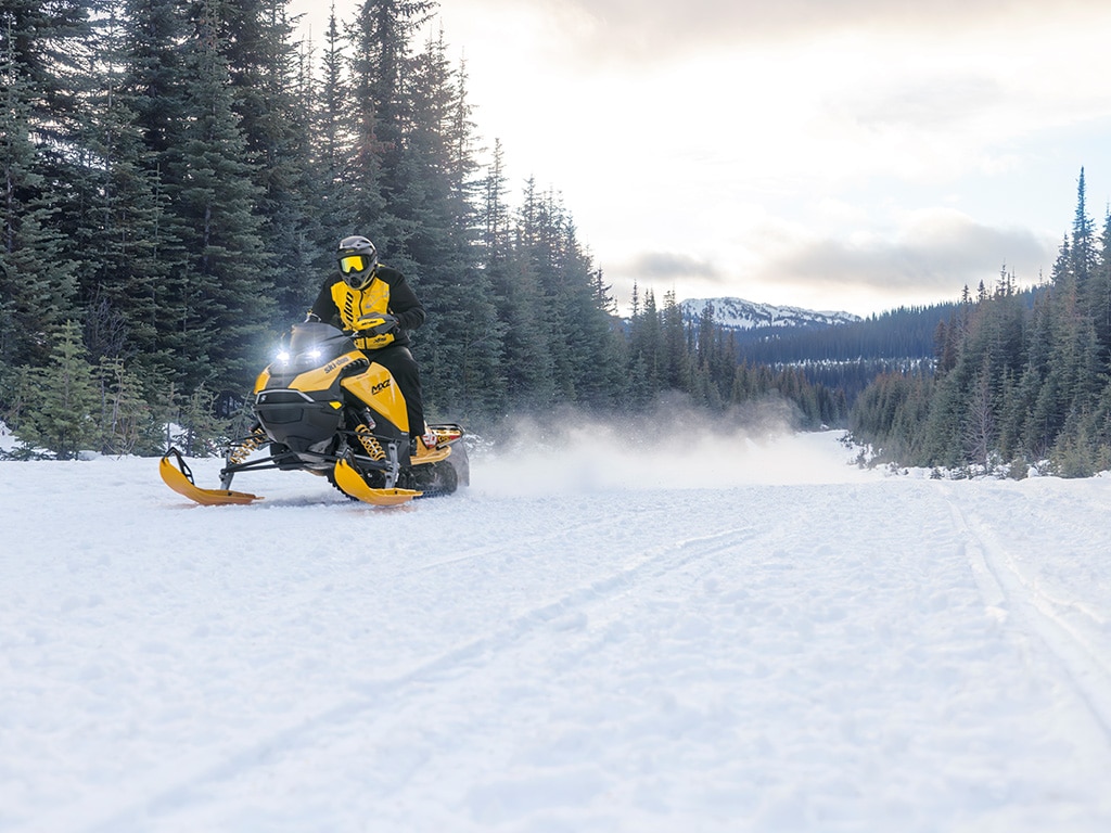 Motoneigiste en randonnée sur un sentier entouré d'arbres en motoneige Ski-Doo MXZ X-RS 2027