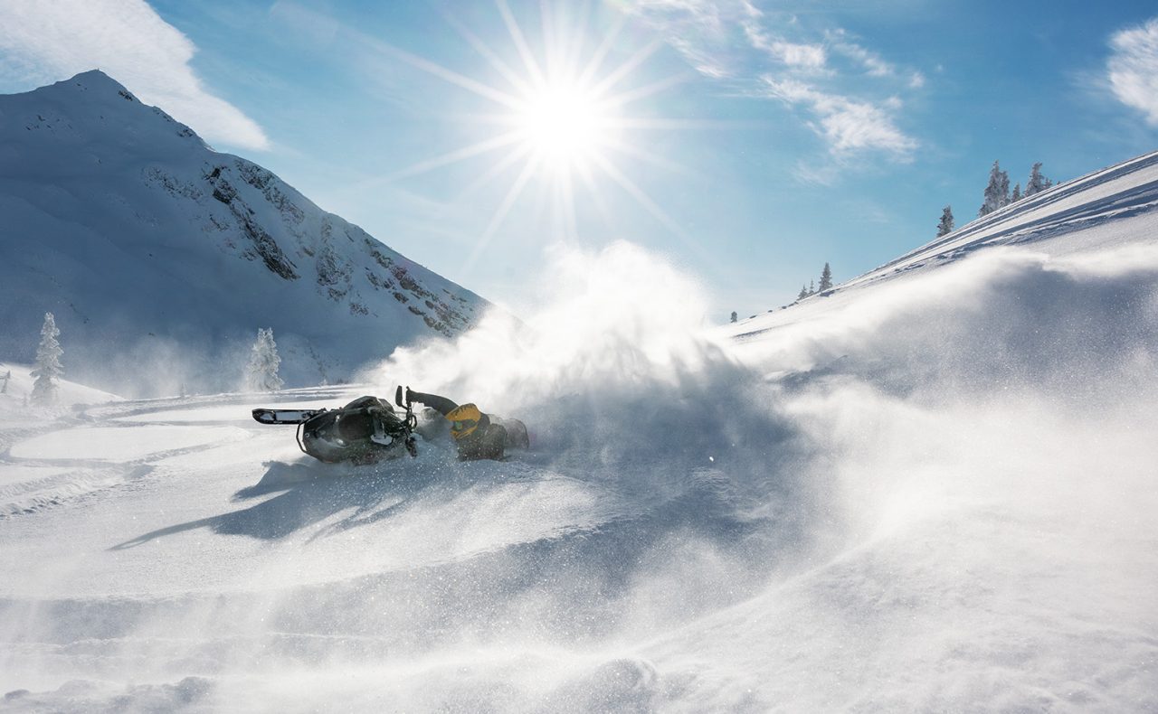 Rider performing a stunt on a 2026 Ski-Doo Summit snowmobile in deep snow