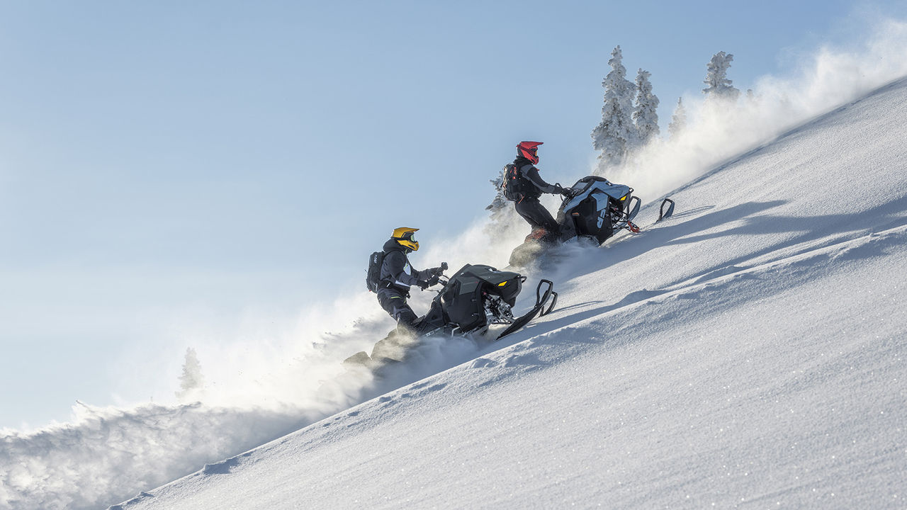 Two 2026 Ski-Doo snowmobiles climbing a steep hill
