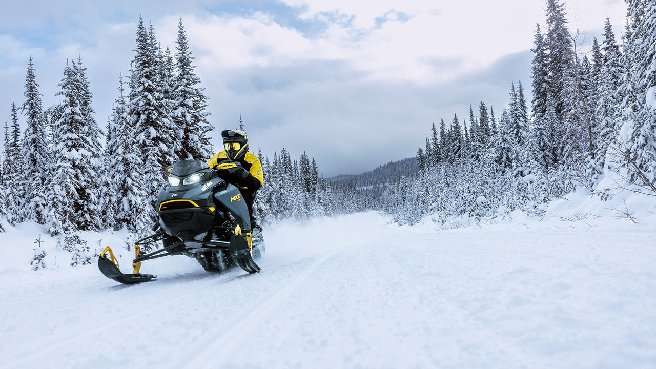 Rider snowmobiling on a snowy trail on a 2026 Ski-Doo MXZ snowmobile